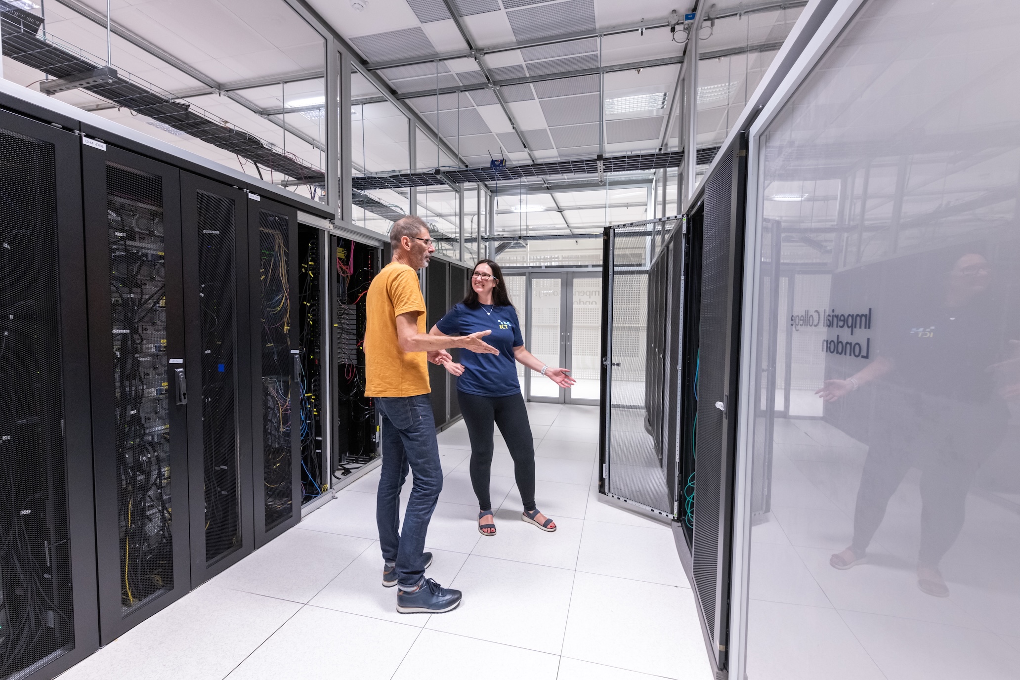 Image of two people standing next to large servers.